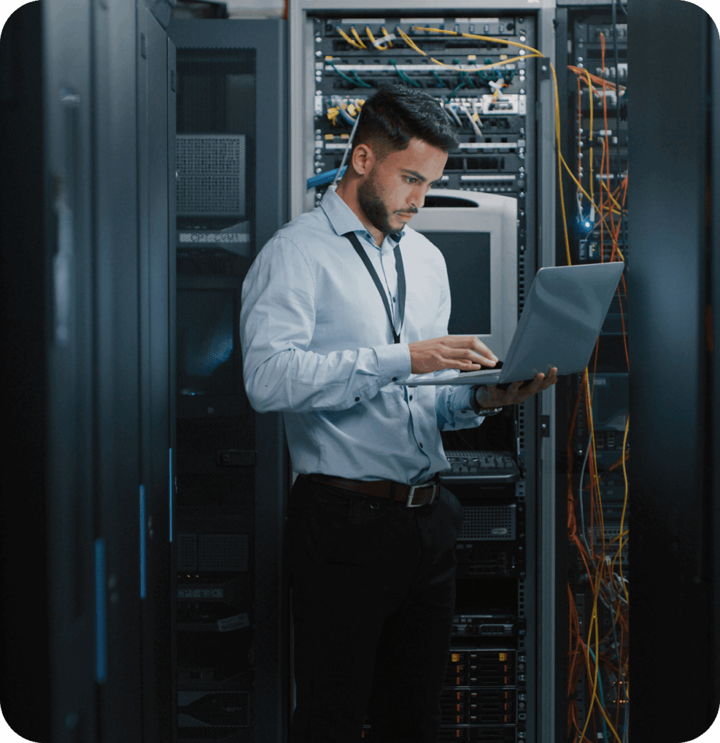 Man working on laptop in server room.