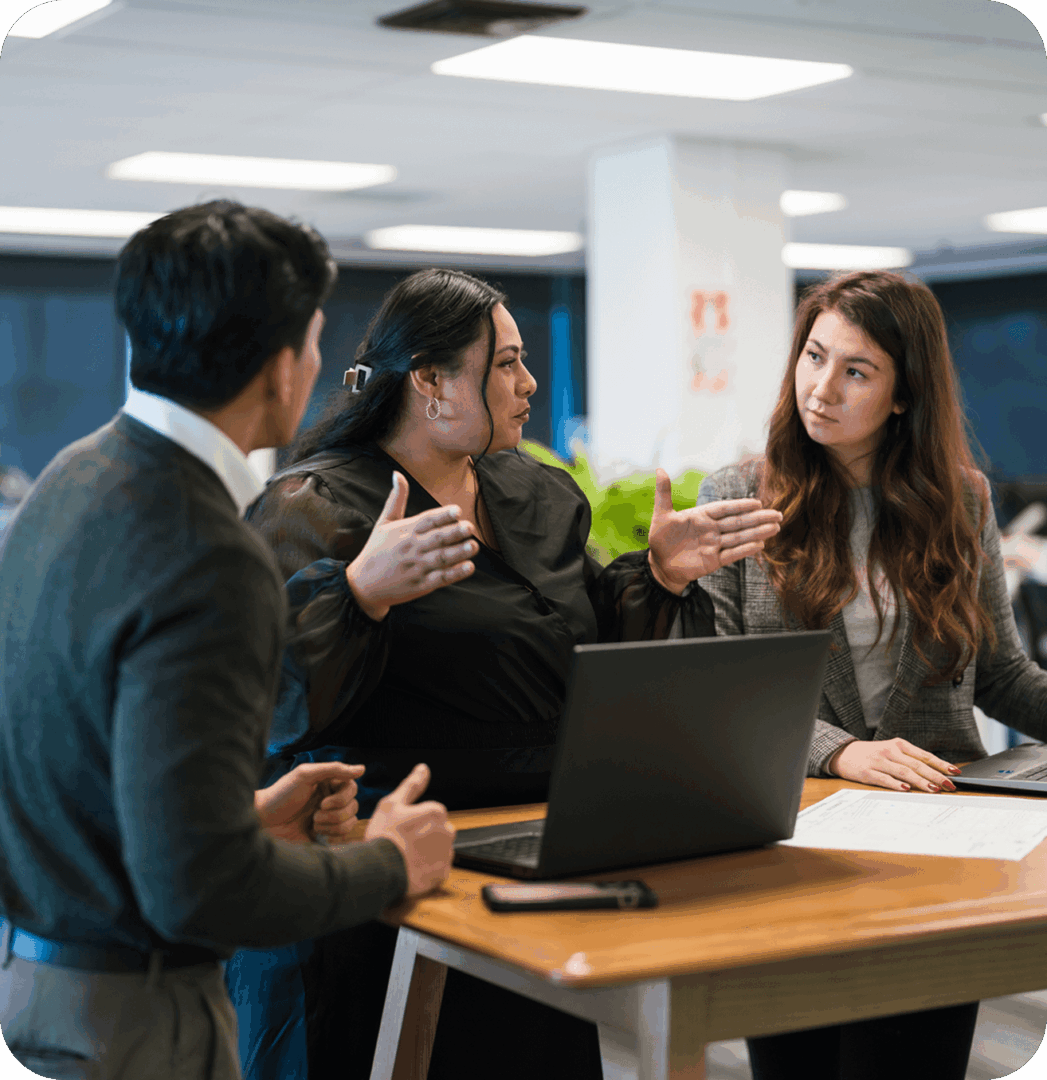 Three colleagues discussing at a desk.
