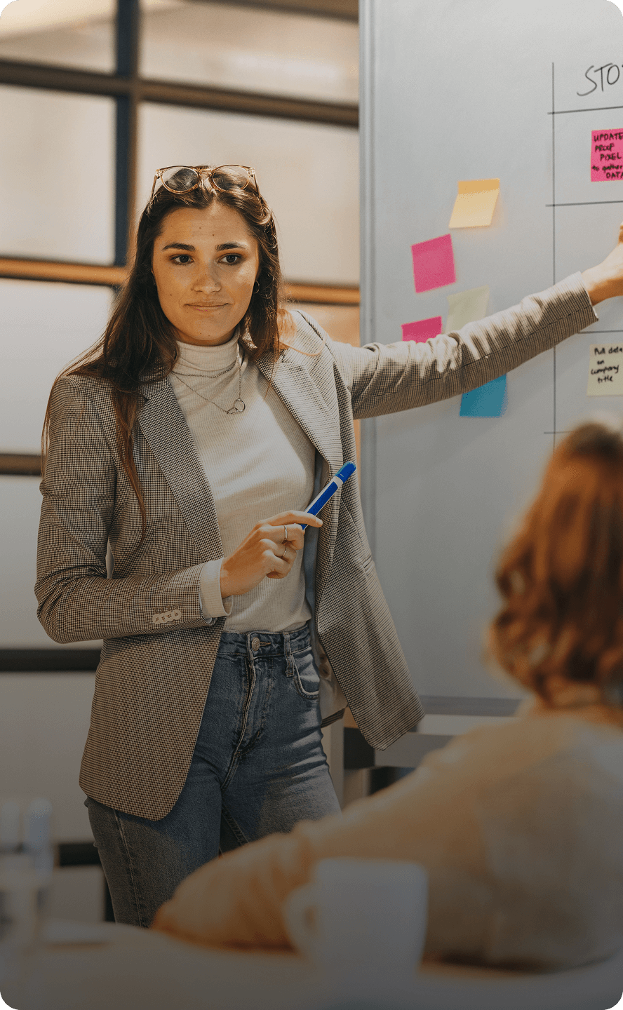 Woman presenting at whiteboard with sticky notes.