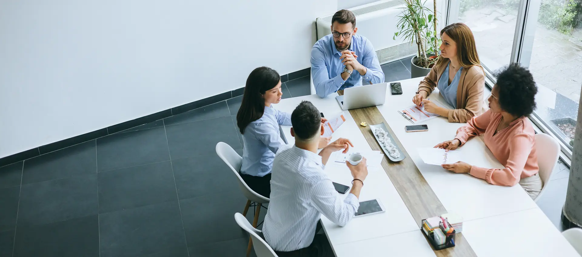 Office meeting with five people at table.